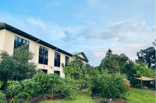 The Creation Village campus building framed by gardens